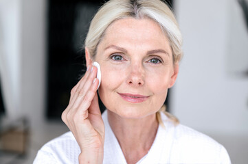 Removing makeup with micellar water and cotton pad disks.
