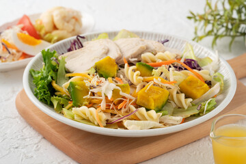 Fresh avocado lettuce salad bowl with chicken meat in a plate on white table background.