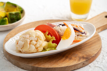 Fresh avocado lettuce salad bowl with chicken meat in a plate on white table background.