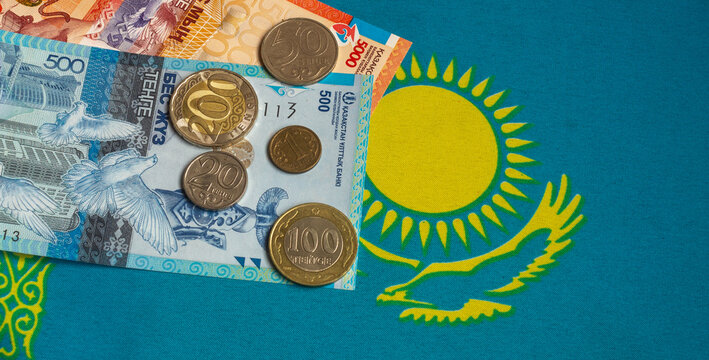 Kazakhstani tenge banknotes and coins with the national flag background