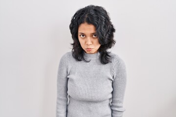 Hispanic woman with dark hair standing over isolated background depressed and worry for distress,...