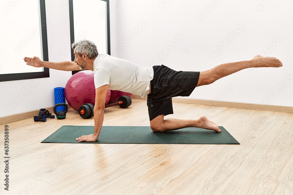 Sticker Middle age grey-haired man stretching back at sport center