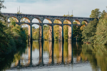 Fototapeta premium Railway Bridge with river in Bietigheim-Bissingen, Germany. Autumn. Railway viaduct over the Enz River, built in 1853 by Karl von Etzel on a sunny summer day. Bietigheim-Bissingen, Germany. Old