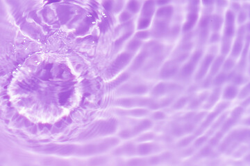 Purple water with ripples on the surface. Defocus blurred transparent pink colored clear calm water surface texture with splashes and bubbles. Water waves with shining pattern texture background.