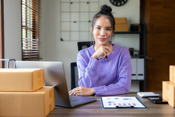Businesswoman working at home with laptop and yellow box Asian woman owns a small business online...