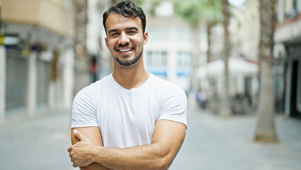 Young hispanic man smiling confident standing with arms crossed gesture at street