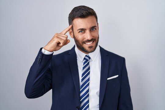 Handsome hispanic man wearing suit and tie smiling pointing to head with one finger, great idea or thought, good memory