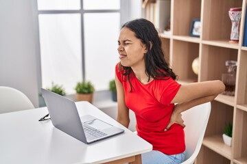 Young african american woman using laptop suffering for backache at home