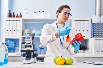 Young beautiful hispanic woman scientist injecting liquid on pepper at laboratory