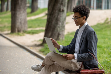 Curly-haired young digital nomad working in the park