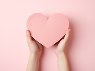 Valentine's Day, pink heart made of paper are held in the hand in love. Top view. Copy space.
