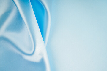 Fototapeta premium The Soft wavy folds of light blue color silk satin background with copy space for your design.