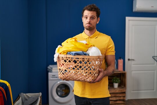 Young hispanic man holding laundry basket depressed and worry for distress, crying angry and afraid. sad expression.