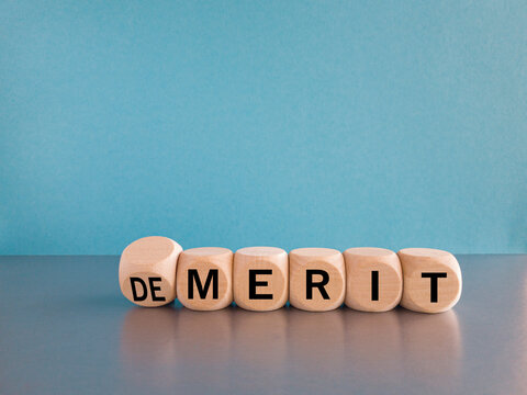Demerit or merit symbol. Male hand flips the wooden cube and changes words demerit to merit. Beautiful blue background, copy space. Business and demerit or merit concept.