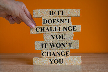 Challenge to change symbol. Concept words If it does not challenge you it won't change you on blocks on a beautiful orange background. Businessman hand. Business motivational and challenge concept.