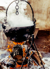 Iron Cooking Pot Suspended Above A Camp Fire