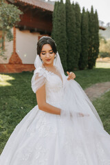 Beautiful bride in a fashionable wedding dress on a natural background in the park. A stunning young bride is incredibly happy. Happy girl on her wedding day