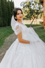 Beautiful bride in a fashionable wedding dress on a natural background in the park. A stunning young bride is incredibly happy. Happy girl on her wedding day