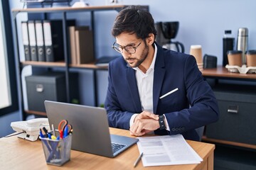 Young hispanic man business worker looking laptop at office