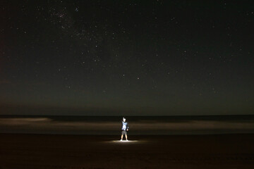 Night photograph of an illuminated man at the seashore, Buenos Aires, Argentina with the stars...