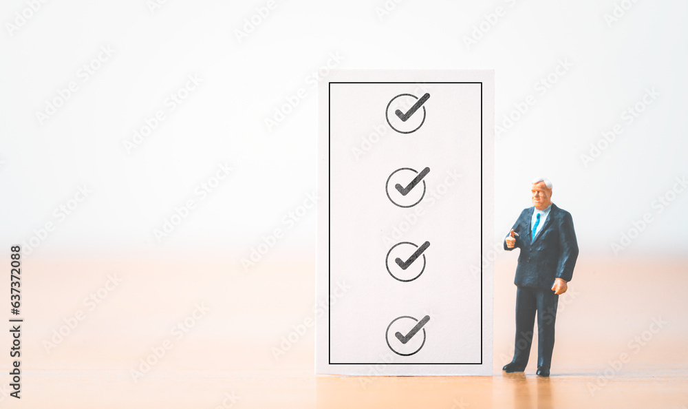 Poster Businessman miniature figure standing with check mark sign on checklist sheet for document audit and project approve concept.
