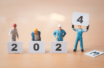 Worker and technician miniature figure standing and showing 2024 year for merry Christmas and happy new year concept.