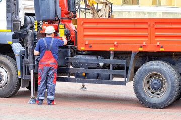 The driver of a truck with a hydraulic manipulator examines and adjusts the operation of the lifting mechanism. - 637372421