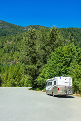 Luxury motorhome with bykes attached to the rack on an asphalt road - obrazy, fototapety, plakaty