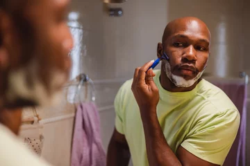 Fotobehang Homem negro se barbeando no espelho do banheiro. Visao traseira e reflexao © Brastock Images