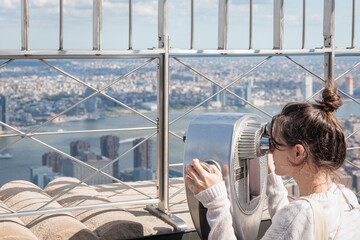 Girl with the Tower Optical viewer at exterior observation deck on Empire State Building, New York, USA