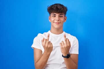 Hispanic teenager standing over blue background showing middle finger doing fuck you bad...