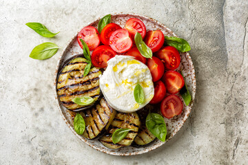 Plate with Burrata or mozzarella cheese and vegetables, grilled eggplant, tomatoes, basils,...