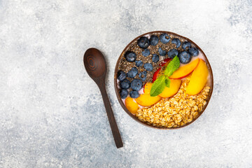 Bowl of granola with yogurt and fresh berries on a texture table. Yogurt berries, acai bowl, spirulina bowl. Healthy food, balanced breakfast. Strawberries, blueberries, kiwi, peach, almonds and chia.
