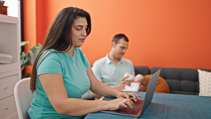Young mother with her family using laptop at home