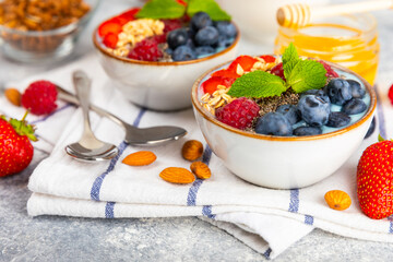 Bowl of granola with yogurt and fresh berries on a texture table. Yogurt berries, acai bowl, spirulina bowl. Healthy food, balanced breakfast. Strawberries, blueberries, kiwi, peach, almonds and chia.