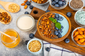 Bowl of granola with yogurt and fresh berries on a texture table. Yogurt berries, acai bowl, spirulina bowl. Healthy food, balanced breakfast. Strawberries, blueberries, kiwi, peach, almonds and chia.