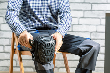 Builder wearing knee protection pads. Concept of safety protective equipment at construction site. Safety at work.