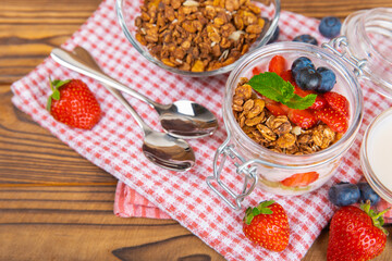 Bowl of granola with yogurt and fresh berries on a texture table. Yogurt berries, acai bowl, spirulina bowl. Healthy food, balanced breakfast. Strawberries, blueberries, kiwi, peach, almonds and chia.