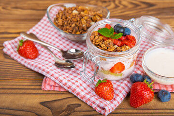 Bowl of granola with yogurt and fresh berries on a texture table. Yogurt berries, acai bowl, spirulina bowl. Healthy food, balanced breakfast. Strawberries, blueberries, kiwi, peach, almonds and chia.