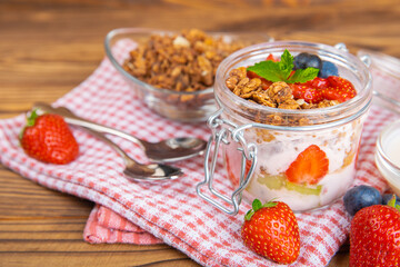 Bowl of granola with yogurt and fresh berries on a texture table. Yogurt berries, acai bowl, spirulina bowl. Healthy food, balanced breakfast. Strawberries, blueberries, kiwi, peach, almonds and chia.