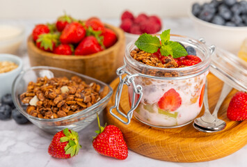 Bowl of granola with yogurt and fresh berries on a texture table. Yogurt berries, acai bowl, spirulina bowl. Healthy food, balanced breakfast. Strawberries, blueberries, kiwi, peach, almonds and chia.