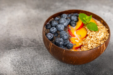 Bowl of granola with yogurt and fresh berries on a texture table. Yogurt berries, acai bowl, spirulina bowl. Healthy food, balanced breakfast. Strawberries, blueberries, kiwi, peach, almonds and chia.