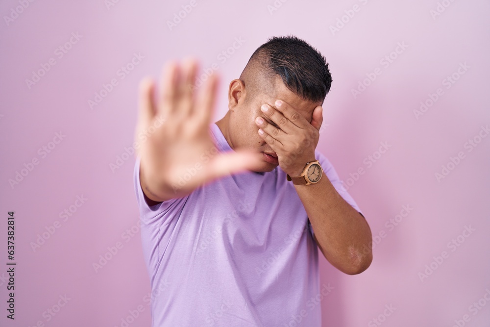 Canvas Prints Young hispanic man standing over pink background covering eyes with hands and doing stop gesture with sad and fear expression. embarrassed and negative concept.