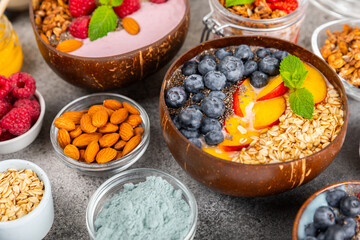 Bowl of granola with yogurt and fresh berries on a texture table. Yogurt berries, acai bowl, spirulina bowl. Healthy food, balanced breakfast. Strawberries, blueberries, kiwi, peach, almonds and chia.