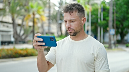 Fototapeta premium Young man using smartphone with serious expression at park