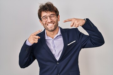 Hispanic business man wearing glasses smiling cheerful showing and pointing with fingers teeth and mouth. dental health concept.