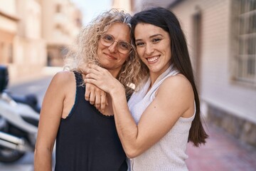 Two women mother and daughter hugging each other at street