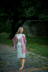 Fototapeta premium Woman in a summer dress with a shawl in a city park.