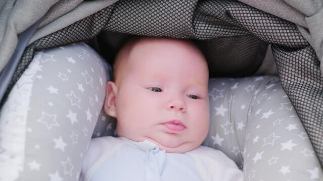 Cute newborn toddler resting in a baby stroller, close-up