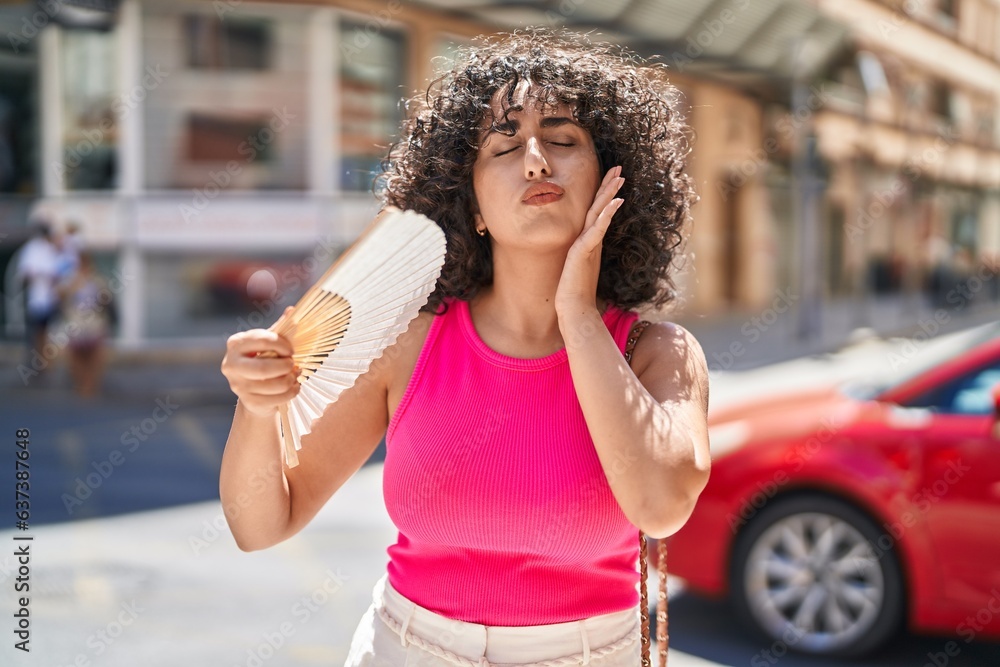 Sticker Young middle eastern woman using handfan suffering for hot at street